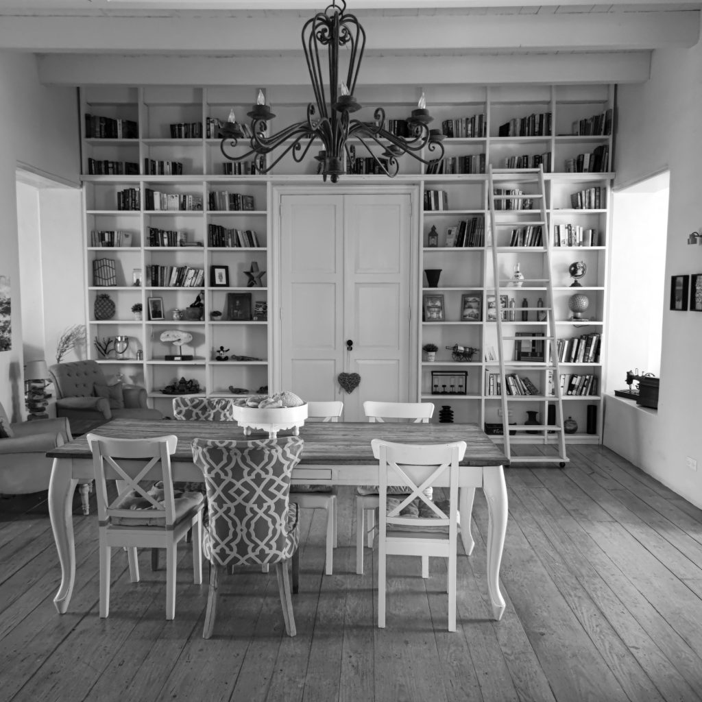 Elegant black and white library interior with wooden floor, chandelier, and bookshelves.